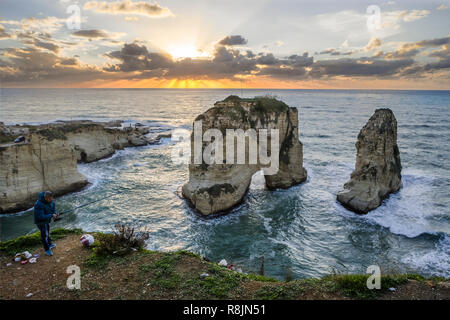 Pêcheur à côté de Pigeon rock au coucher du soleil, Rawche, Beyrouth, Liban Banque D'Images