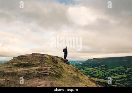 Un homme avec un sac à dos à la recherche à travers le paysage de champs et de collines du haut d'une colline sur l'anglais, frontière galloise. Montagne Noire, Pays de Galles. Banque D'Images