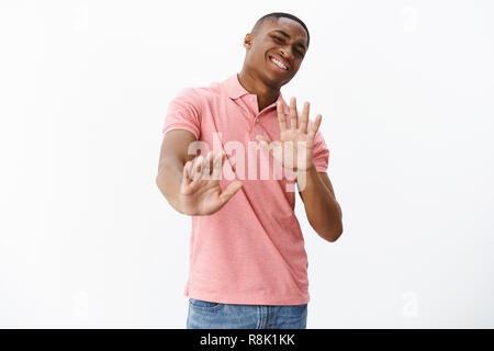 Guy pense qu'il passe. Indifférent african american man pas disposés à participer à partie qui soulève les mains près de la poitrine et aucun signe de refus l'arrière avec flexion sourire maladroit mais rejette d'offrir Banque D'Images