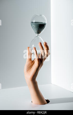 Portrait of woman holding hourglass avec sable gris dans la main à travers le trou à White Banque D'Images