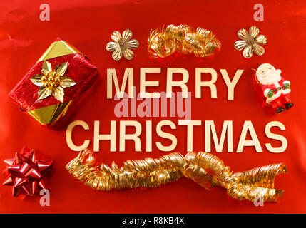 Joyeux Noël écrit en lettres en bois et des décorations de Noël sur fond rouge Banque D'Images