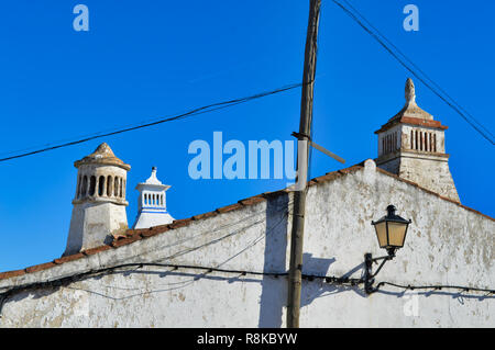 Cheminées traditionnels portugais sur le toit d'une maison ancienne, avec une lampe de rue, un pôle de puissance et les câbles sur le côté, dans la région de Cacela Velha, Algarve Banque D'Images