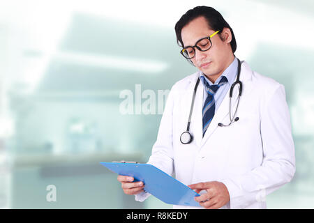 Photo image portrait d'un jeune homme asiatique médecin portant des lunettes, à la lecture, à son patient notes Banque D'Images