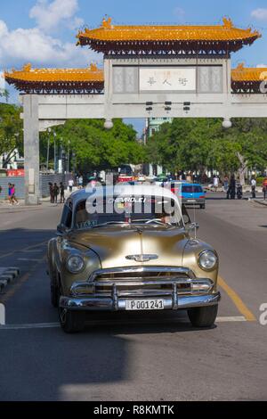 Cuba, province de Ciudad de la Habana, La Havane, district de Centro Habana, bicitaxi et voitures américaines sous le portique monumental Chino porte de Chinatown, qui chevauche la Calle Dragones Banque D'Images