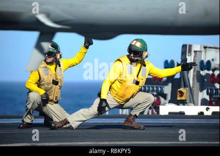 Les directeurs de vol connu comme chemises jaunes, un signal F/A-18 Super Hornet pour lancer à bord du poste de pilotage de la classe Nimitz porte-avions USS Harry S. Truman le 7 décembre 2018 dans l'océan Atlantique. Chemises jaunes sont portés par les gestionnaires d'aéronefs Aéronefs, administrateurs, officiers et catapulte Agents Arrêt considéré comme le plus difficile et important travail sur le poste de pilotage. Banque D'Images