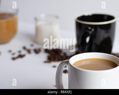 Vue sur table du petit déjeuner avec plusieurs tasses de café et de crème avec les grains de café sur un tableau blanc avec blur Banque D'Images