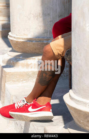 Détail de jeunes tatoués les jambes, assis au soleil à La Havane, Cuba Banque D'Images
