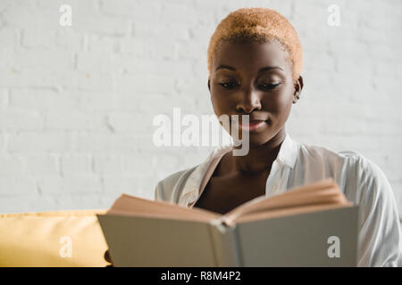 Close up of african american woman reading book avec les cheveux courts Banque D'Images