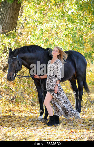 Jeune femme en robe a la mode des chevaux de race de selle Banque D'Images
