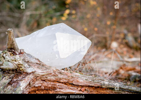 Très gros cristal de quartz pose dans l'herbe près de la plage d'un lac au coucher du soleil Banque D'Images