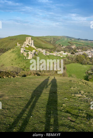 Ombre d'un couple tenant les mains marchant vers le château de Corfe sur l'île de Purbeck, Dorset, Angleterre, Royaume-Uni Banque D'Images