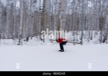 Skieur lumineux dans une veste rouge et un chapeau avec un pompon montè sur un arrière-plan flou en mouvement forest Banque D'Images