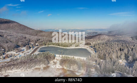 Volant au-dessus de l'hiver neigeux Misty Mountain Forest couvertes de neige . Vue de dessus, le paysage avec brouillard dérive à travers les arbres dans la matinée. Banque D'Images