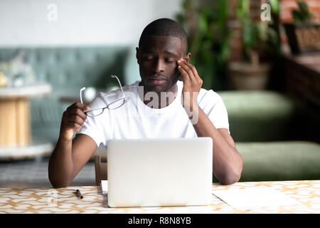 Fatigué African American man taking off lunettes, sentir la fatigue oculaire Banque D'Images