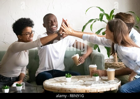 Professionnels divers amis haute donnant cinq ensemble dans cafe Banque D'Images