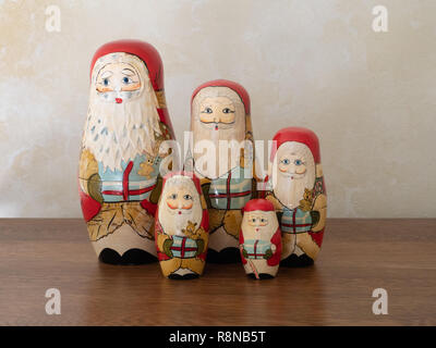 Une famille de poupées en bois peint à la nidification Santa holding gifts. Photographié sur une surface en bois au niveau de l'oeil. Banque D'Images