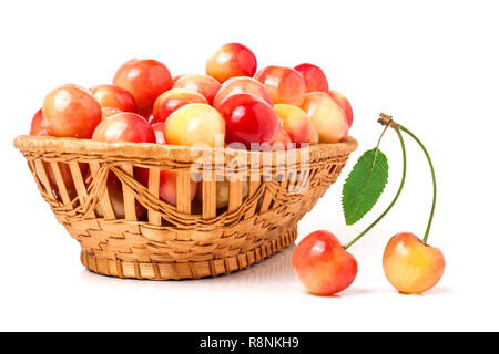 Cerises jaunes dans un panier en osier isolé sur fond blanc Banque D'Images