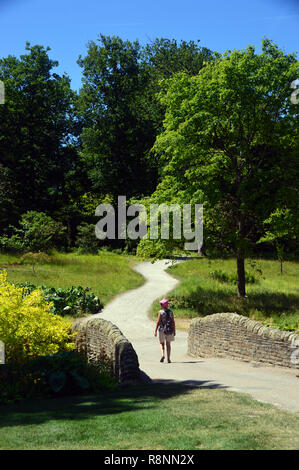 Lone Woman Walking on Path au pont de pierre, à sec RHS Garden Harlow Carr, Harrogate, Yorkshire. UK. Banque D'Images
