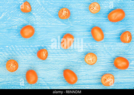 Cumquat kumquat ou avec la moitié bleu sur fond de bois. Vue d'en haut. Motif de mise à plat Banque D'Images