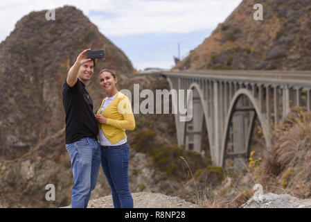 Un jeune couple s'en face de selfies le pont du ruisseau Big, Big Sur, Californie, USA Banque D'Images