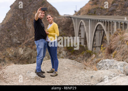 Un jeune couple s'en face de selfies le pont du ruisseau Big, Big Sur, Californie, USA Banque D'Images