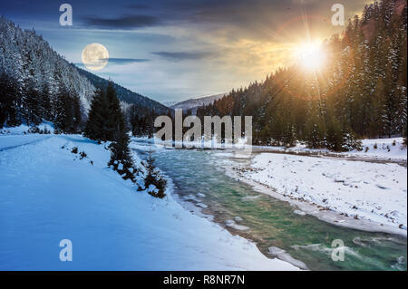 Changement d'heure jour et nuit. concept de la rivière de montagne en hiver avec le soleil et la lune. la neige a couvert les berges. forêt dans la neige sur la montagne nuage lointain. Banque D'Images