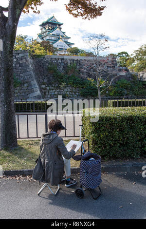 Une femme âgée s'inspire du château d'Osaka au Japon Banque D'Images