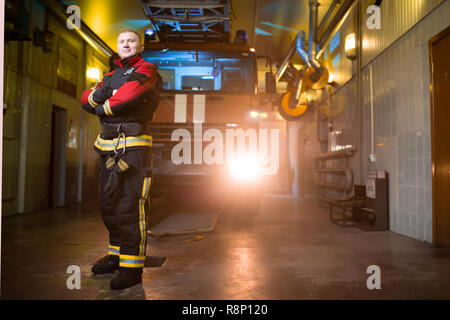 Photo de pompier pleine longueur avec les bras croisés sur fond de camion d'incendie Banque D'Images