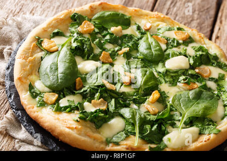 Fine cuisine italienne avec pizza épinards frais, l'ail et fromage sur un conseil sur une table horizontale. Banque D'Images