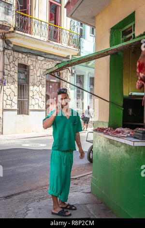 Jeune homme on cellphone en attente à La Havane Cuba boucher dans la rue Banque D'Images