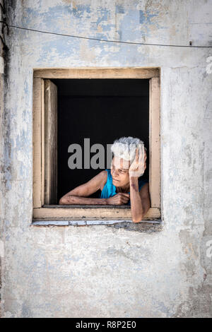 Vieille Femme cubaine incliné vers l'extérieur de la fenêtre de la rue à La Havane Cuba Banque D'Images