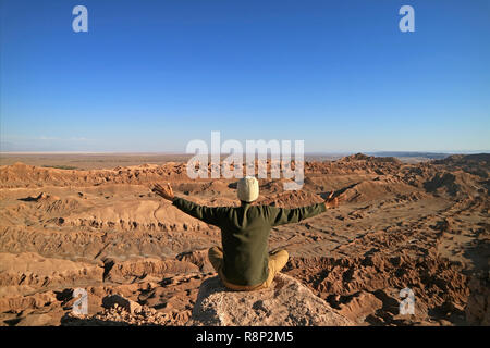 Homme assis sur le rocher Raising Arms appréciant la magnifique vue sur la vallée de la Lune ou Vallée de la Lune, Désert d'Atacama, San Pedro Atacama, Chili Banque D'Images
