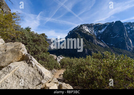 Vue sur Half Dome, Yosemite National Park, situé contre le ciel bleu zébré de traînées de vapeur. Banque D'Images