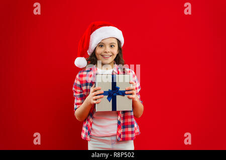 Les achats de Noël. La célébration du nouvel an. Santa Claus kid. Heureux vacances d'hiver. Petite fille. Présent pour Noël. L'enfance. Petite fille enfant à santa red hat. Profitant des ventes de Noël. Banque D'Images