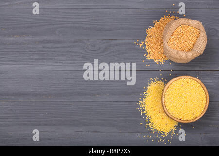 Millet dans bol en bois, de sacs et d'épillets vert sur le fond en bois noir avec l'exemplaire de l'espace pour votre texte. Vue d'en haut Banque D'Images