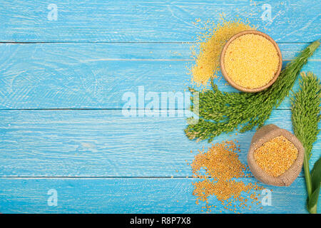 Millet dans bol en bois, de sacs et d'épillets vert sur le fond en bois bleu avec l'exemplaire de l'espace pour votre texte. Vue d'en haut Banque D'Images