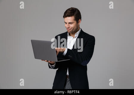 Libre de 30s en fonction de la joie lors de l'utilisation d'ordinateur portable isolé sur fond gris Banque D'Images
