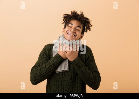 Portrait of african american man wearing sweater et écharpe de toucher la gorge sur fond beige isolés Banque D'Images