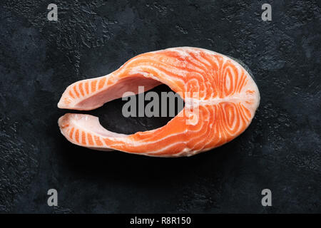 Pavé de saumon cru frais sur fond de béton noir, vue du dessus. Poisson cru steak Banque D'Images