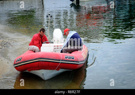Neos Marmaras, péninsule de Sithonia, Halkidiki, Grèce, le 16 juin 2018 : deux hommes dans le bateau de sauvetage en caoutchouc rouge contrôle de bateau sur la baie de Neos Marmaras Banque D'Images