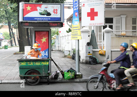 Ho Chi Minh Ville, Vietnam - nettoyage balayeuse de route à proximité de Parti communiste des affiches célébrant 43 années depuis la ville fut libérée en 1975 Banque D'Images