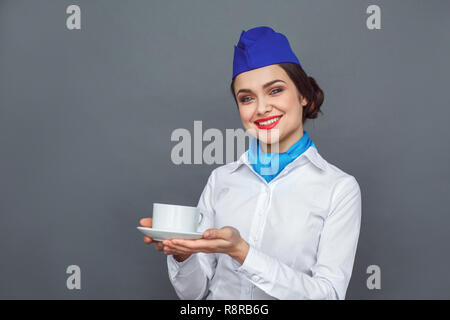 L'occupation professionnelle. Hôtesse de l'isolés sur gris servant café chaud smiling friendly Banque D'Images