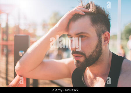 Portrait de guy remise en forme fatigué sur jour ensoleillé chaud. sport homme se reposant après un entraînement intensif. Banque D'Images