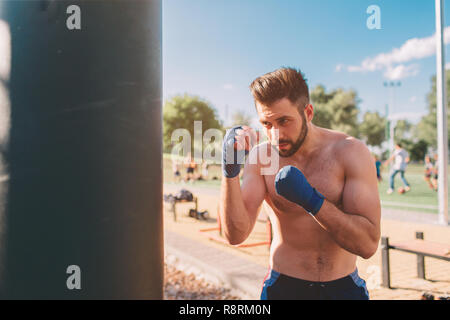 Jeune homme d'entraînement de boxe. Exercice Boxer boxer boxe athlétique. Concept main punch par sac de boxe. Banque D'Images