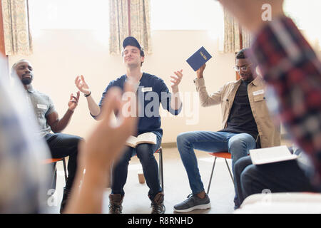 Les hommes avec bible priant avec bras levés en groupe de prière Banque D'Images