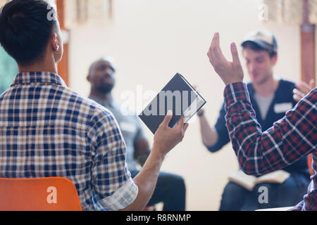 Les hommes avec bible priant avec bras levés en groupe de prière Banque D'Images