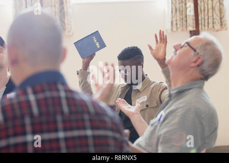 Les hommes avec bible priant avec bras levés en groupe de prière Banque D'Images