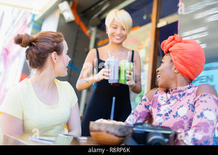 Les smoothies waitress à women friends at sidewalk cafe Banque D'Images
