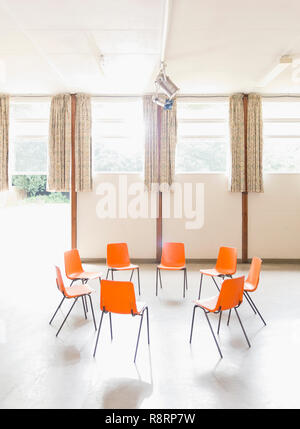 Chaises Orange disposés en cercle au centre communautaire Banque D'Images