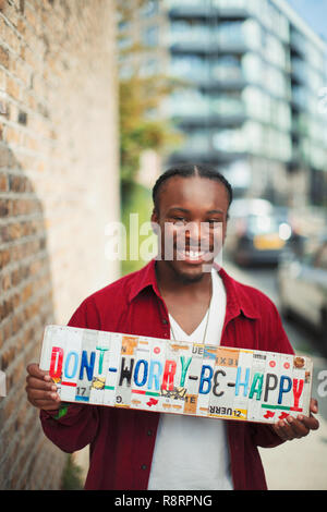 Portrait of smiling teenage boy holding dont Worry Be Happy plaques Banque D'Images